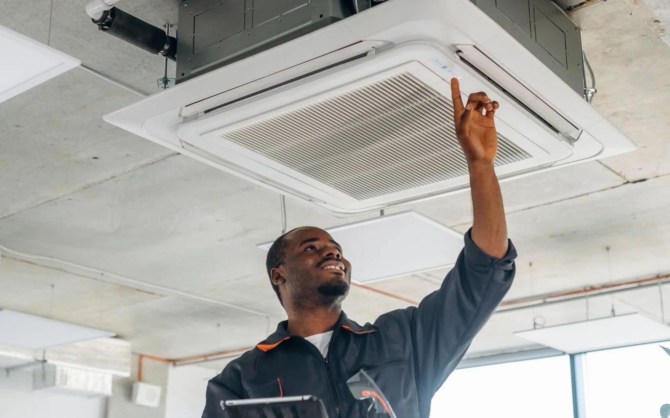 Technician inspecting a commercial ceiling air-conditioning unit and electrical supply