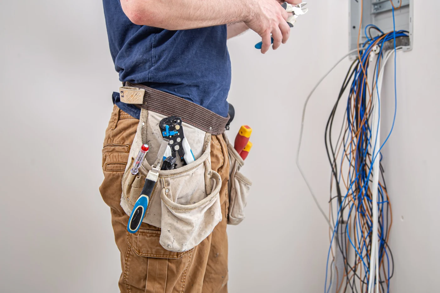 Electrician working on commercial switchboard wiring and electrical cable connections
