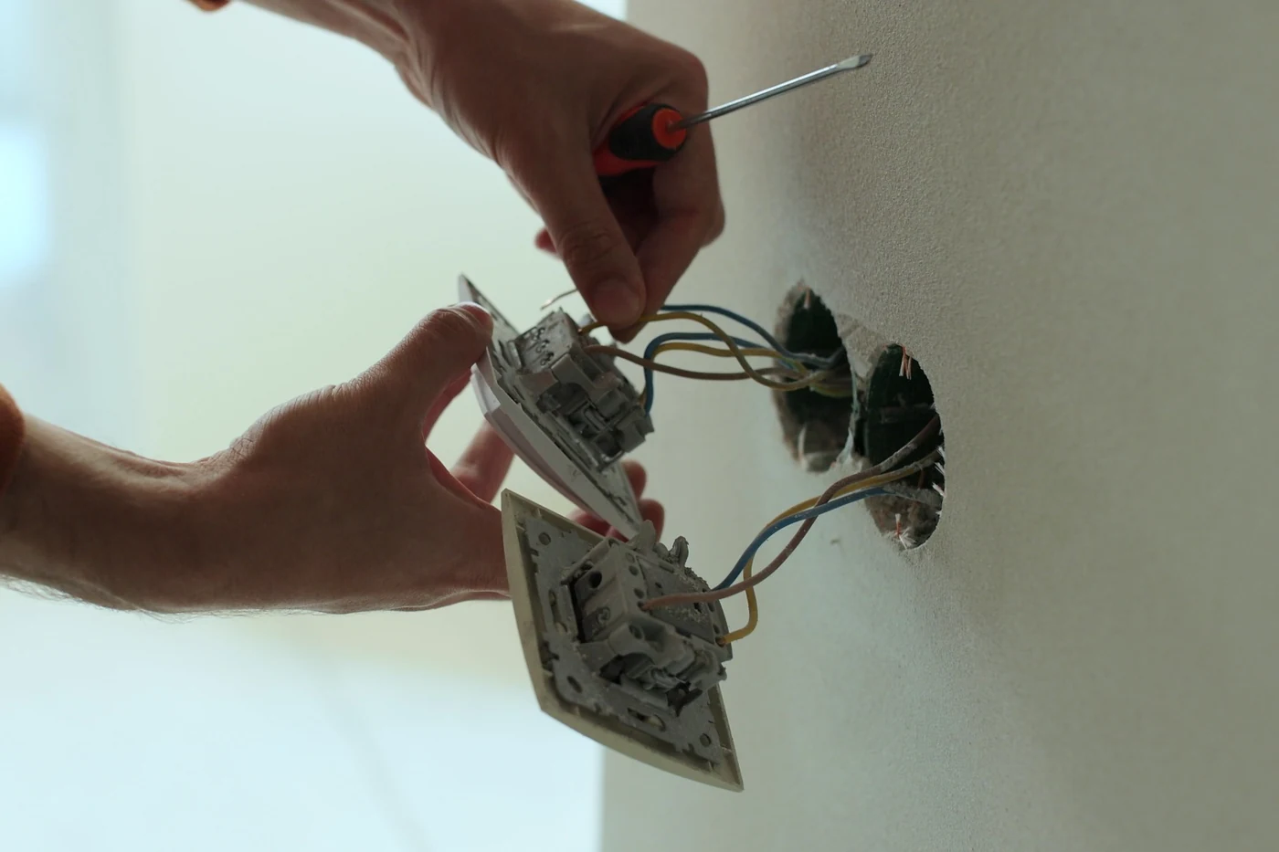 Plug point lighting and circuit installation electrician in Gauteng Electrician inserting wiring into a socket outlet during electrical installation work