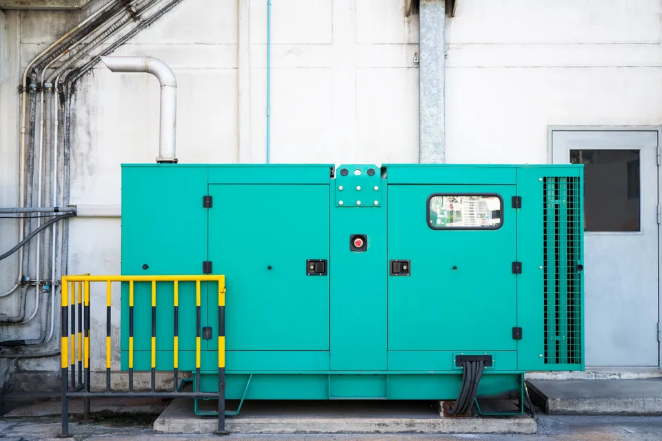 Large industrial generator installed beside a factory for three-phase backup power Large industrial generator installed beside a factory for three-phase backup power