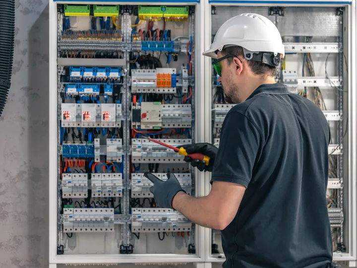 Commercial electrician inspecting a large electrical control and distribution panel