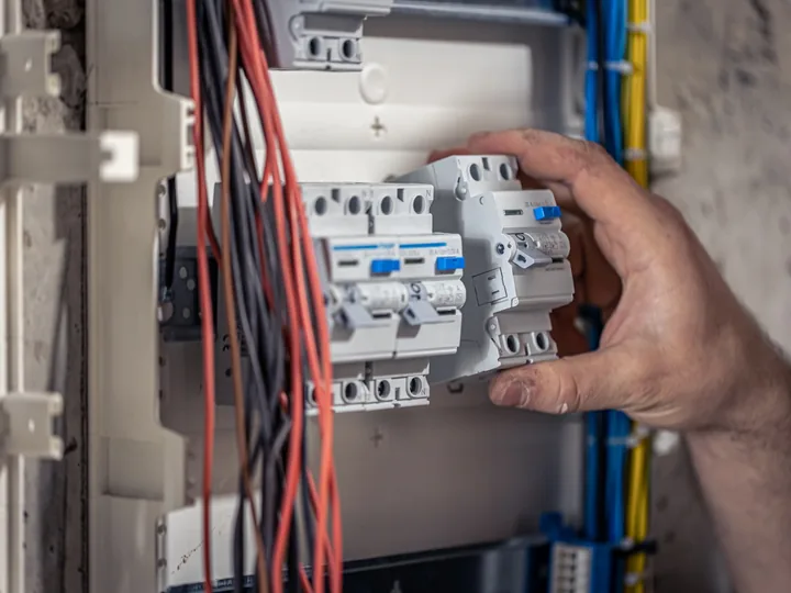 Electrician working on circuit breakers inside an electrical distribution board