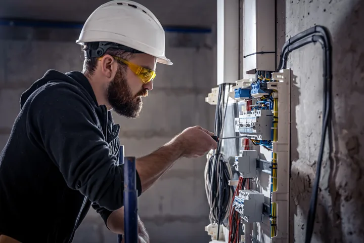 Emergency electrician inspecting an electrical panel for an urgent electrical fault