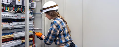 Industrial three-phase switchgear control panel inspection and electrical distribution work in Gauteng Industrial electrician working inside a large three-phase switchgear and electrical control panel