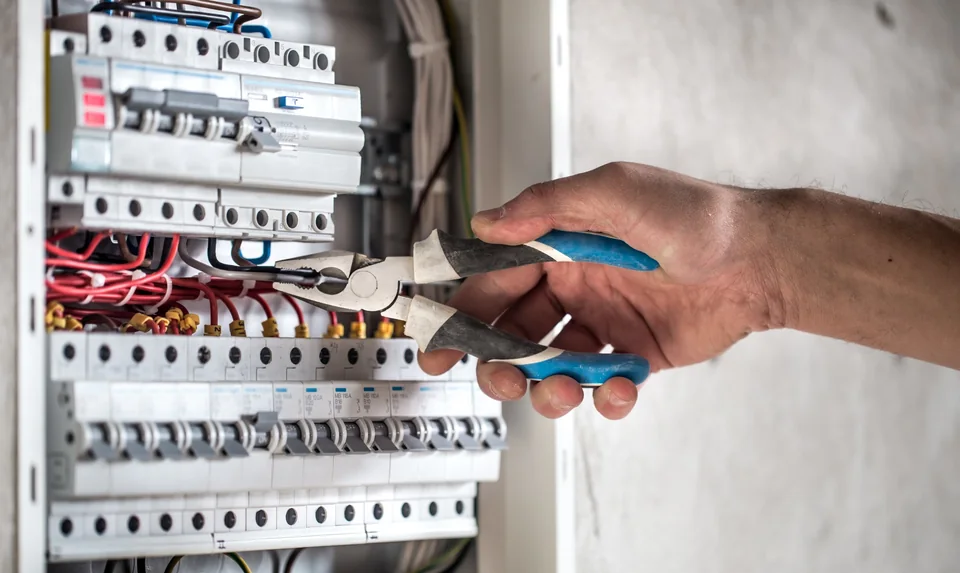 Licensed electrician working on circuit breakers in a distribution board