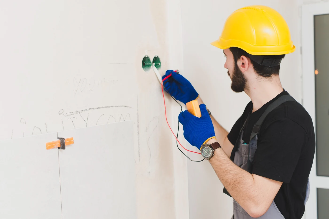 Electrician testing and preparing wall wiring for an additional plug point installation