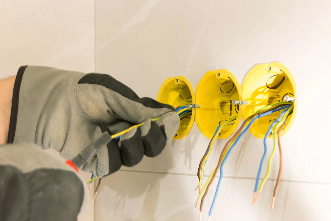Electrician fitting and checking wall receptacle wiring during electrical safety work