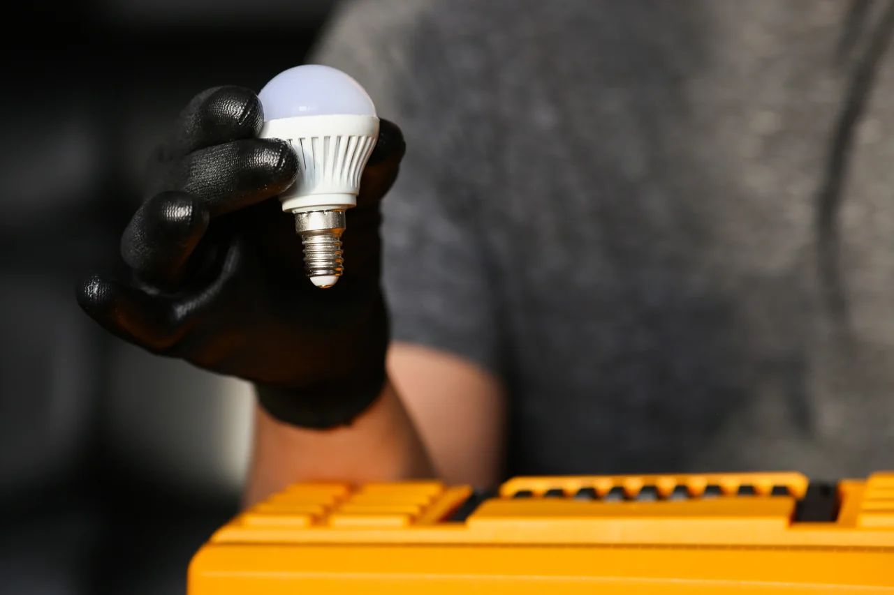 Residential lighting installation and repairs in Gauteng Electrician holding an LED light bulb for residential lighting installation and repairs