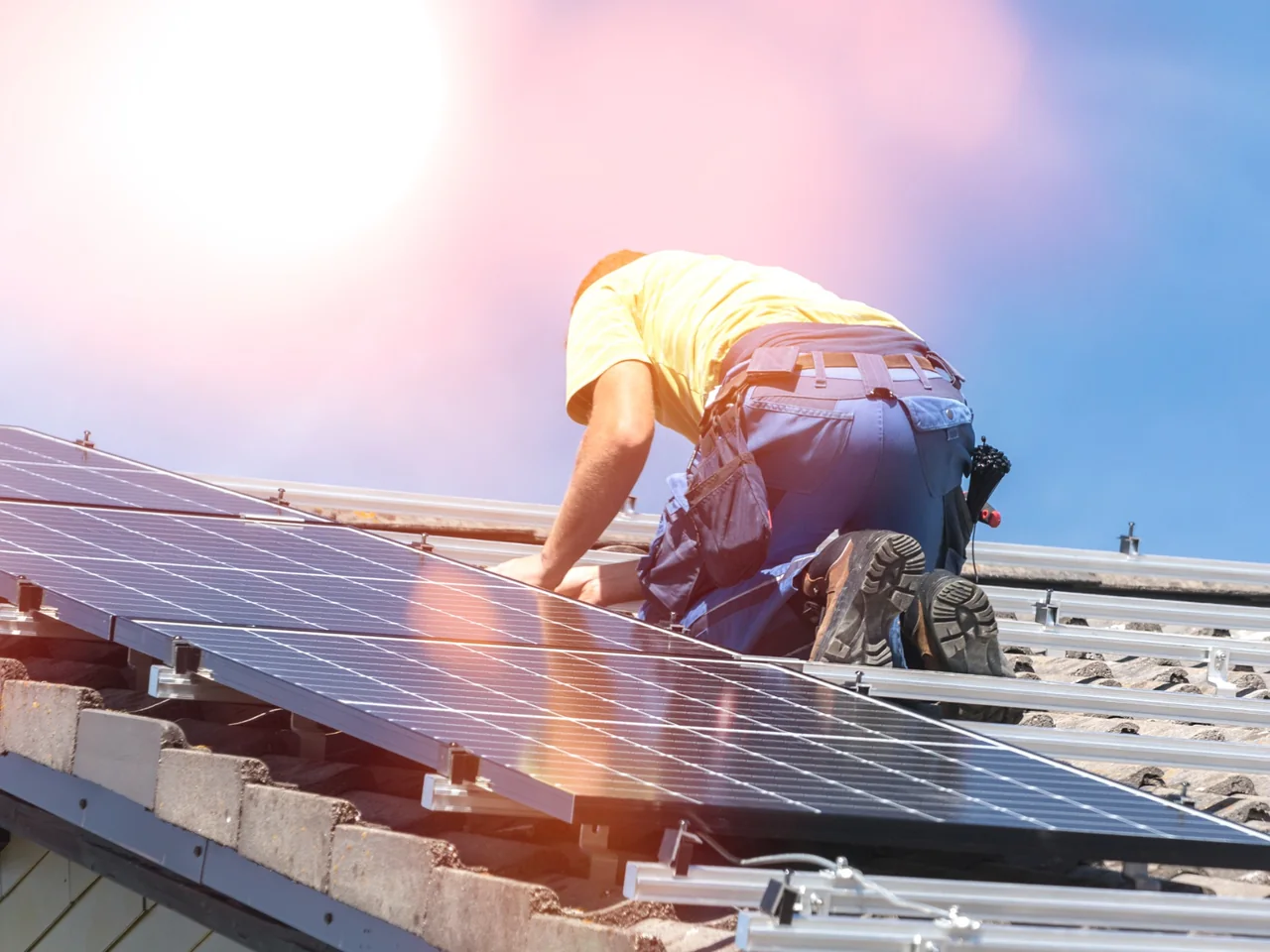 Solar installer working on rooftop solar panels as part of electrical installation work